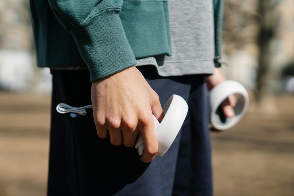 Crop anonymous male playing with white round shaped controller on blurred background in daytime