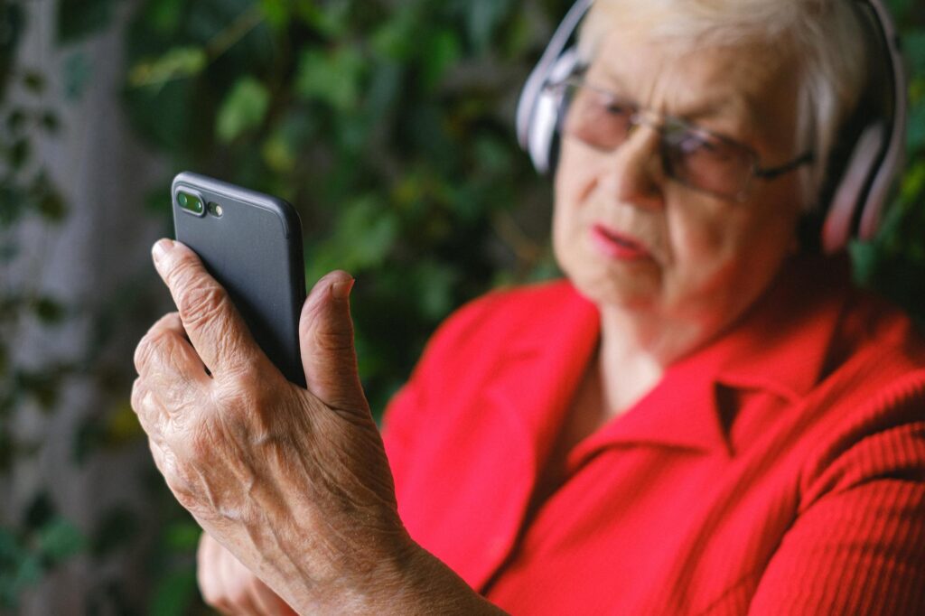 A Man in Red Shirt Using a Phone while Wearing Headphones