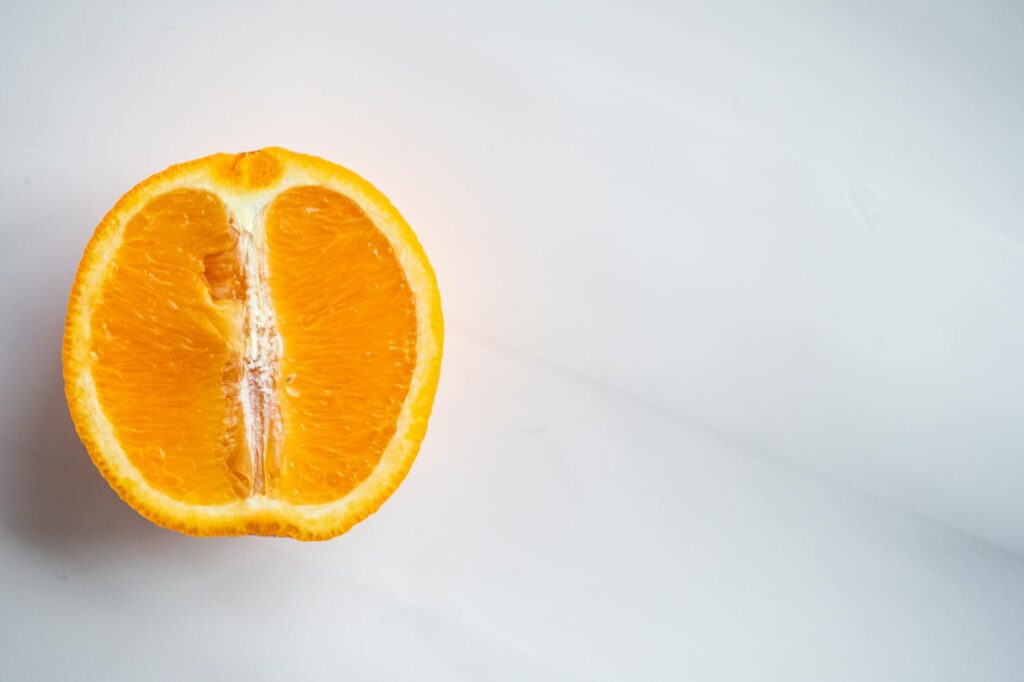 From above of bright cut citrus fruit full of vitamin with orange peel on table