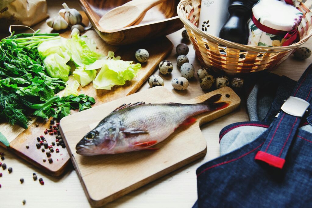 Raw fish on cutting board with lettuce in kitchen