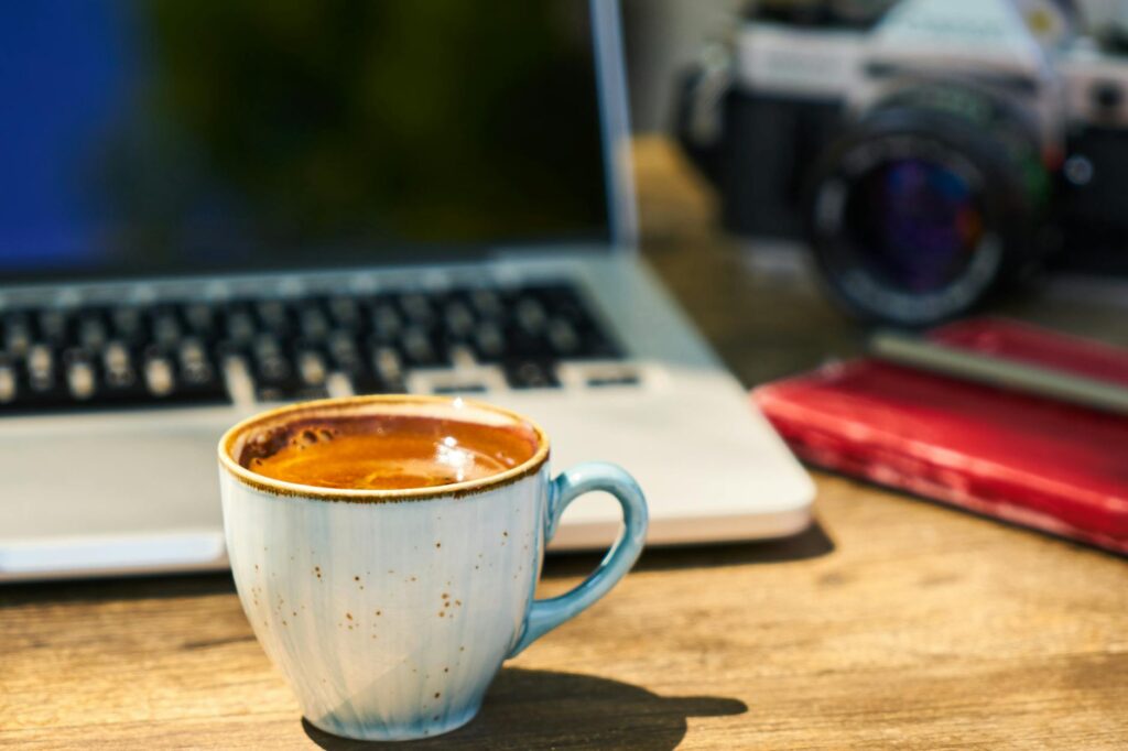 A cup of coffee and a camera on a wooden table in the workplace