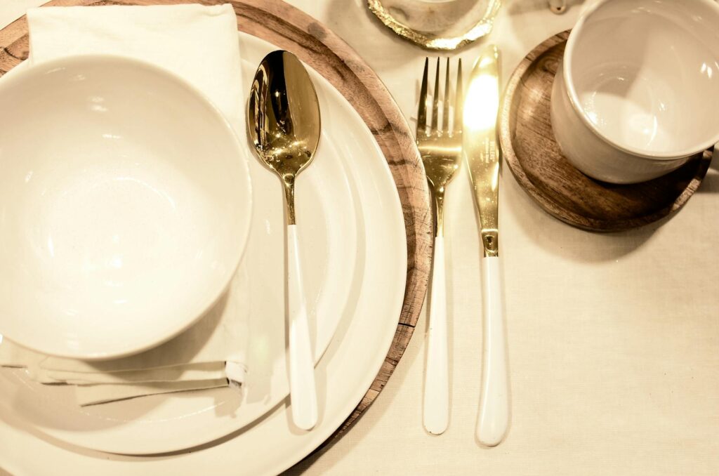 From above of porcelain dishware with napkin and wooden stand on served table during celebration