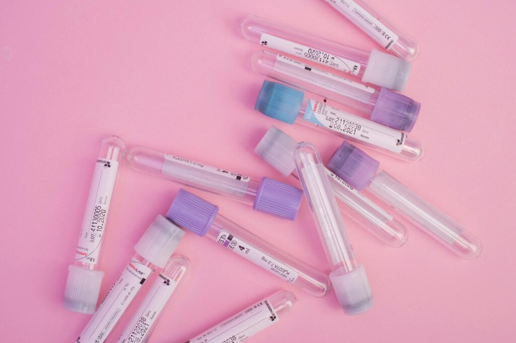 Set of blood test vials arranged on pink table