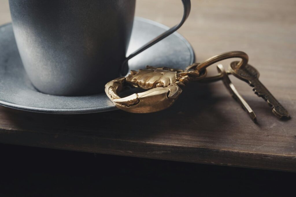 Clsoe-up of Keys with a Golden Crab Keychain Lying next to a Cup