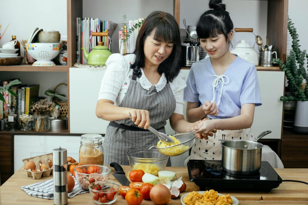 Happy women making pasta in light kitchen