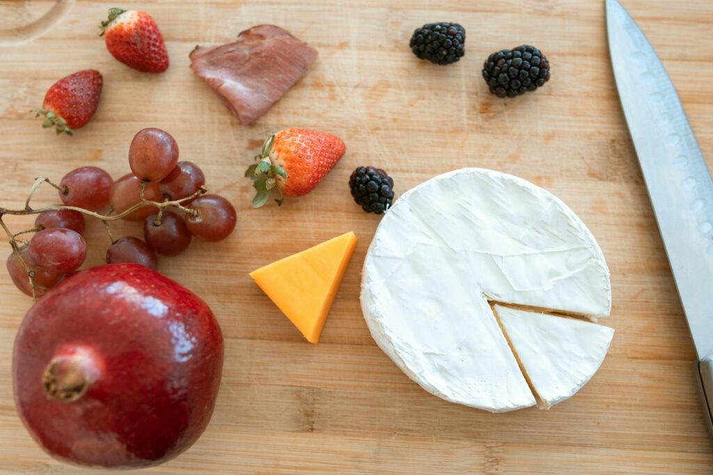 Sliced Cheese and Strawberries on Brown Wooden Chopping Board