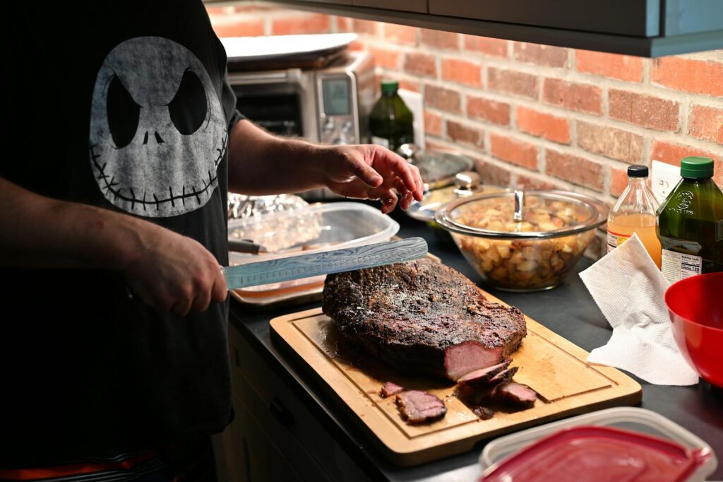 A man is cutting up a steak on a cutting board